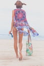 Woman tourist walking on a tropical summer vacation beach wearing sunglasses and beach bag relaxing on travel holidays Royalty Free Stock Photo