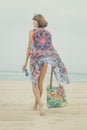 Woman tourist walking on a tropical summer vacation beach wearing sunglasses and beach bag relaxing on travel holidays Royalty Free Stock Photo