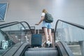 Traveler woman with luggage in airport standing on escalator go to gate for journey. Royalty Free Stock Photo