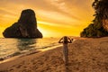 Woman tourist in white dress and hat walking on Phra nang Cave Beach at sunset, Railay, Krabi, Thailand. vacation, travel, summer