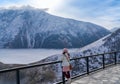 woman tourist in winter clothes standing and watching the fantastic scenery of the Caucasus mountains from the viewpoint at