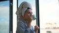 Woman with towel on head drinking coffee in background of window. Concept. Beautiful young woman preparing for start of