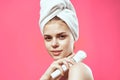 woman with towel on head naked shoulders skin care cosmetology pink background
