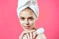 woman with towel on head naked shoulders skin care cosmetology pink background