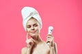 woman with towel on head naked shoulders skin care cosmetology pink background