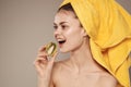 Woman with a towel on her head bare shoulders kiwi in hands health vitamins rejuvenation