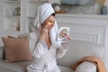 Woman in with towel on her head looks in mirror and applies golden plasters Royalty Free Stock Photo