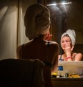 Woman with a towel on her head makes a make-up in front of a mirror