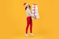 woman with tower of Xmas holiday boxes on yellow backdrop