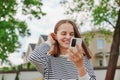 Woman in town browsing internet on smart phone making selfie having video call smiling happily browsing internet outdoor touching Royalty Free Stock Photo