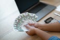 Woman trader counting cash, holding bunch of euro, home office