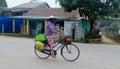 Woman in traditional Asian conical hat on bycicle