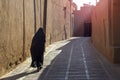 A woman in traditional black Islamic clothing walks the empty morning street of the eastern city. Royalty Free Stock Photo