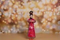 A woman in a traditional Chinese dress on the background of fireworks welcomes guests. The concept of the Chinese New Year. A doll