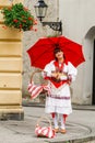 Woman in traditional Croatian dress holding a red umbrella