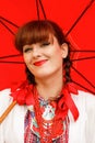 Woman in traditional Croatian dress holding a red umbrella