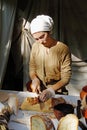 Woman in traditional dress and handkerchief cutting bread at the festival `Times and epochs` in Moscow