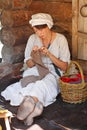 A woman in traditional dress and headscarf engaged in needlework at the festival `Times and epochs` in Moscow