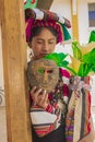 Woman with traditional typical dress and flowers in her hand and wooden mask