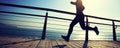 Sporty female runner running on seaside boardwalk during sunrise Royalty Free Stock Photo