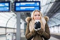 Woman in train station in winter warming up with a hot coffee