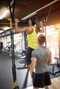 Woman trained in gym with coach- back view