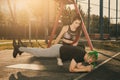 Woman trainer with braids hairstyle helping man man with mohawk hairstyle doing exercise outdoors using overhead training Royalty Free Stock Photo