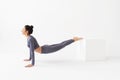 A woman trainer in sportswear, performs a deflection to stretch the muscles of the back, stands on her arms and leans on a cube