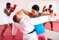 Woman and trainer train painful hold on self-defense course in boxing gym