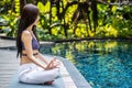 Woman training yoga and meditation in a lotus yoga position at blue swimming pool Royalty Free Stock Photo