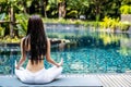 Woman training yoga and meditation in a lotus yoga position at blue swimming pool Royalty Free Stock Photo