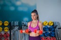 Woman trains in the gym with dumbbells and demonstrates athletic shape