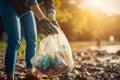 Woman with trash bag picking up plastic bottle at morning park. Generate Ai