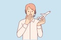 Woman travel agent holds airplane and covers mouth, feeling shocked by information about plane crash