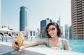 Woman travel blogger takes a selfie photo on her smartphone while relaxing in the pool on the roof of a skyscraper in