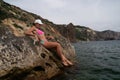 Woman travel sea. Pink bikini tourist captures sea memory, posing on beach amidst volcanic mountains for travel