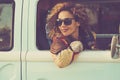 Woman travel with vehicle and looking outside the window smiling and enjoying road trip alone. Concept of classic van renting