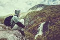 Woman traveler with backpack hiking in Norway mountains with magnificent waterfall