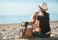 Woman traveler with backpack holding dog and looking at sea.