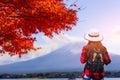 Woman traveler with backpack looking to Fuji mountains and red maple in Autumn, Japan