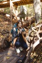 Woman traveler with backpack and retro film camera making picture in autumn forest. Nature photographer Royalty Free Stock Photo