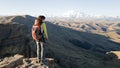 Woman traveler with backpack standing on the edge of the cliff on a plateau Bergamet with a view to the Elbrus mountain. Travel Royalty Free Stock Photo