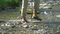 The woman the traveler with a backpack and sticks for tracking passes a mountain stream.