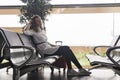 Woman traveler with baggage sits in the waiting room of the airport or train station and is waiting for the flight Royalty Free Stock Photo