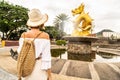 Woman traveler with boho backpack and hat looking at the gold dragon monument in Thailand. Tourism