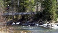 Woman traveler is on bridge over mountain river in spring. Media. Traveler crosses iron bridge over mountain river Royalty Free Stock Photo