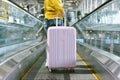 Woman traveler carry big suitcase on escalator walkway at the airport terminal.