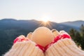 Woman traveler in christmas gloves holding snowball on a background of mountains with sunbeams. Winter travelling concept.