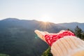 Woman traveler in christmas gloves holds out a hand to mountains with sunbeams. Winter travelling concept.