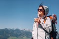 Woman traveler drinks tea on the mountain top